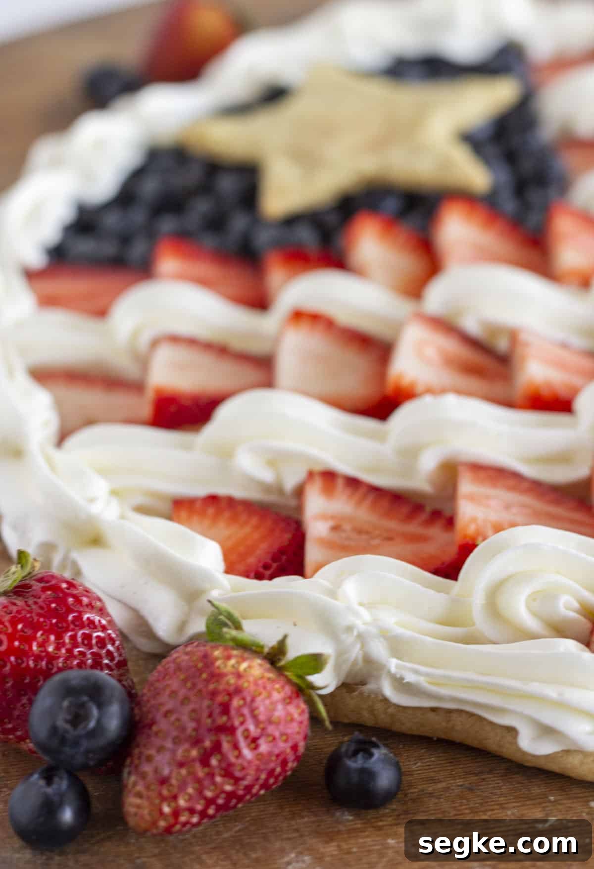 Close-up detail of the fresh fruit flag pizza showing strawberries, blueberries, and piped frosting.
