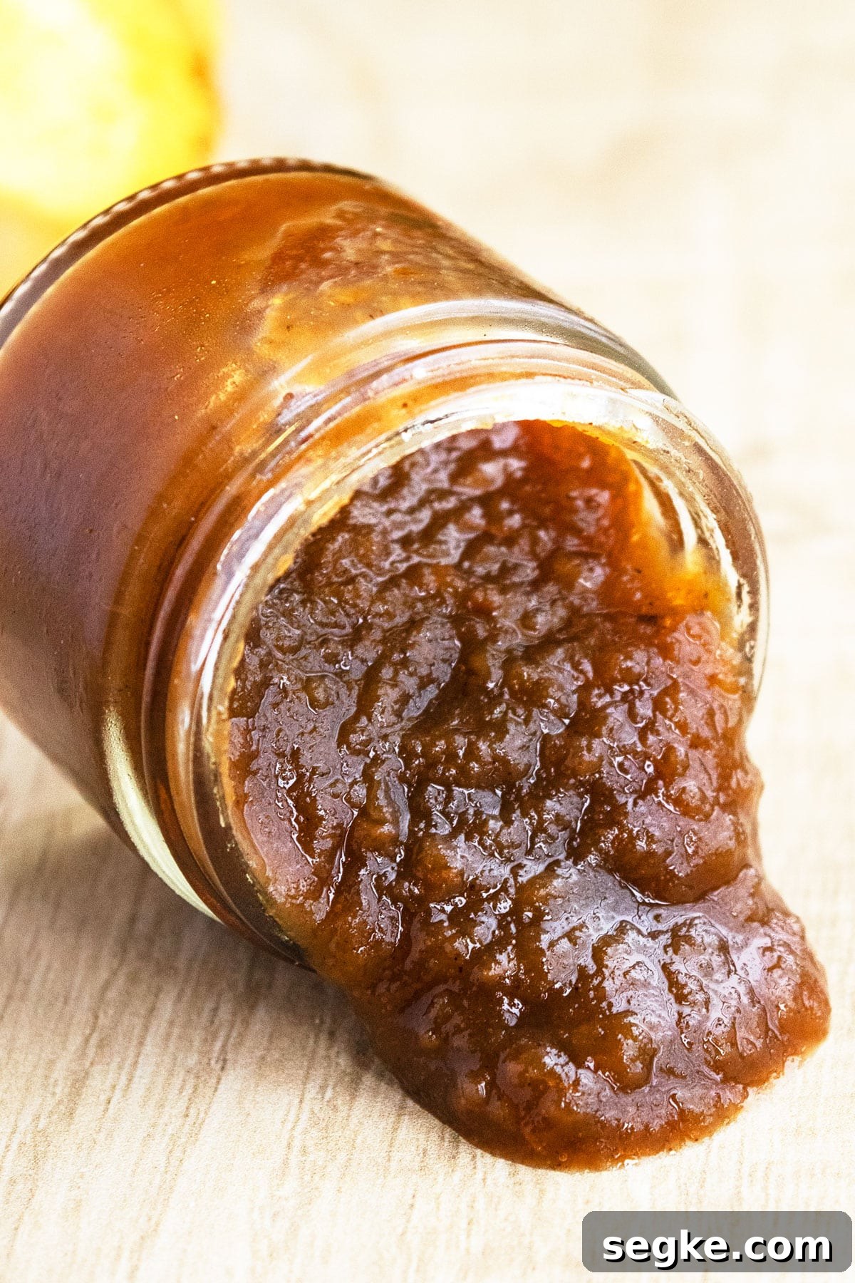 Homemade Spiced Butter Spilling From Glass Jar on Rustic Brown Table.