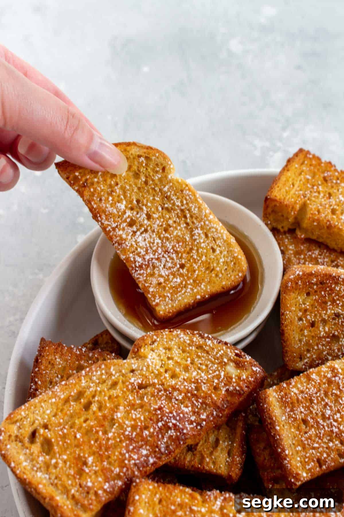A air fryer french toast sticks dipped into maple syrup.