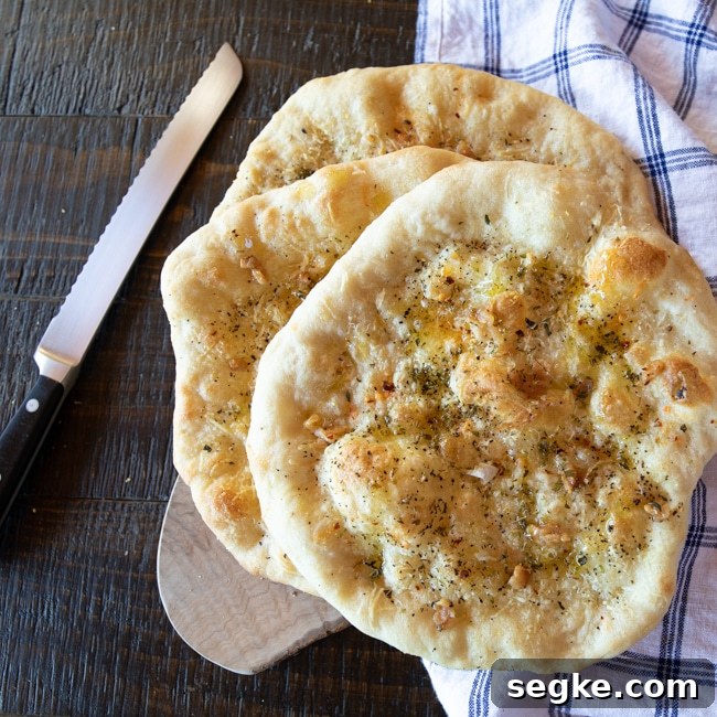 Pizza Aglio e Olio: Garlic and Olive Oil Pizza Bread Recipe 2 Three rounds of baked pizza bread seasoned aglio and olio style on a cutting board.