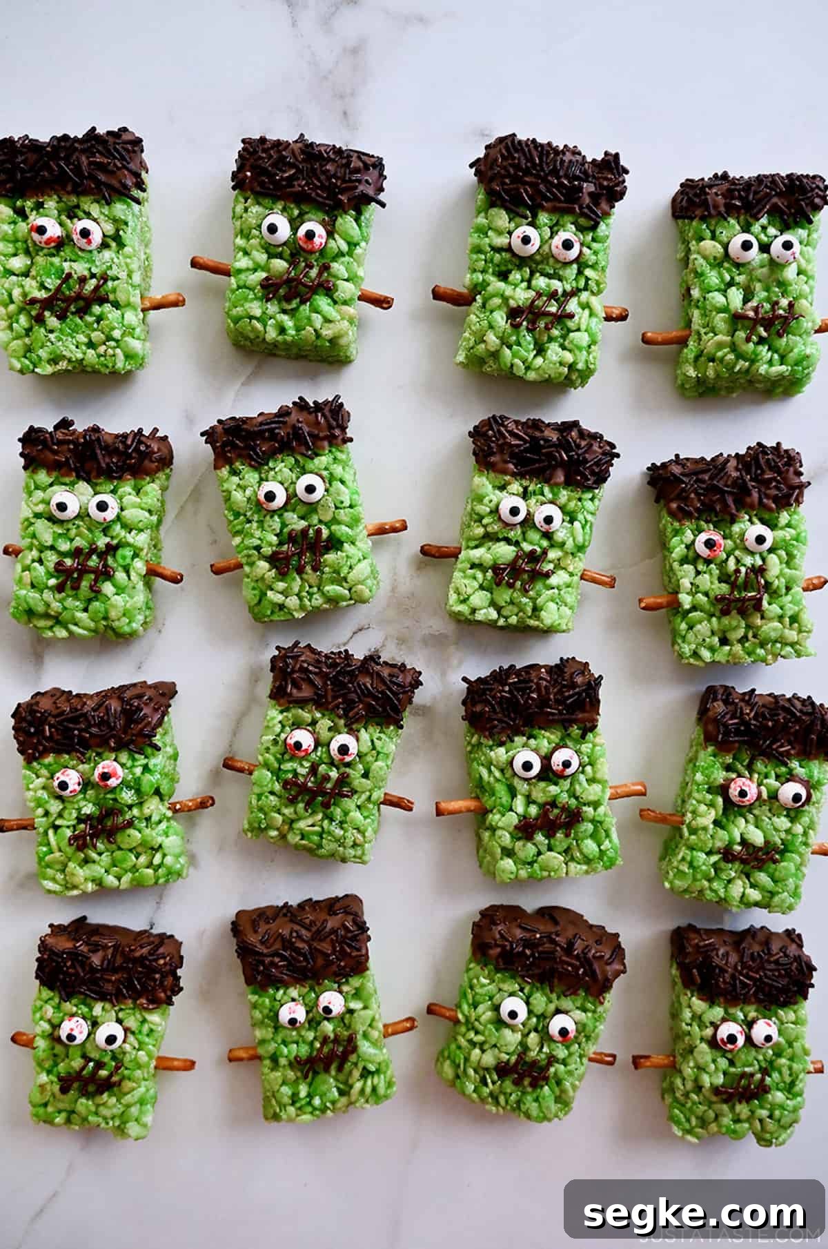 Spooky Halloween Dessert Recipes to Impress Guests 5 Four rows of Frankenstein Rice Krispie treats with candy eyes and pretzel stick bolts.