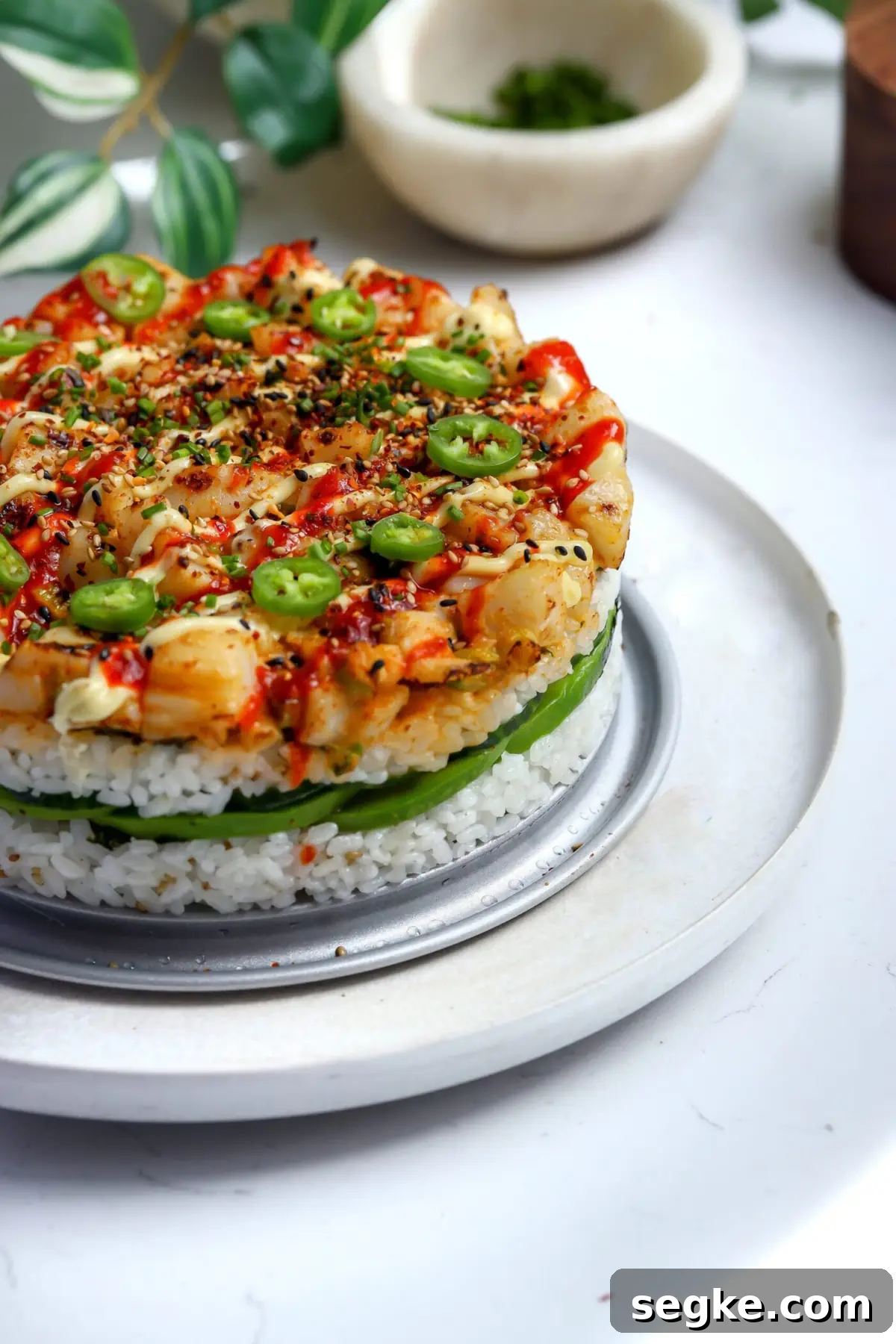 Baked sushi cake with spicy scallops broiled until caramelized, topped with Japanese mayo, sriracha, shichimi togarashi, and serrano slices.