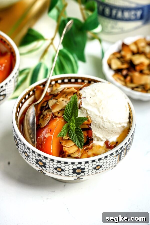 caramelized Amaretto Peaches with toasted almond in a bowl, topped with ice cream and mint. This dessert can be made gluten, dairy and lactose free.