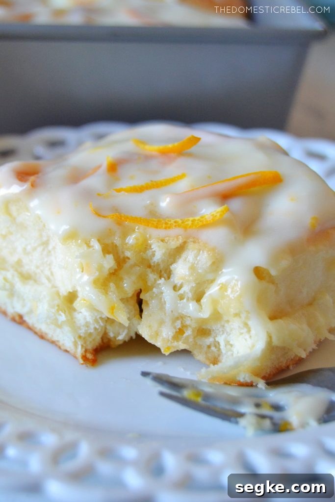 Zesty Orange Glazed Sweet Rolls Recipe 3 Orange sweet roll on a white lace plate with a fork