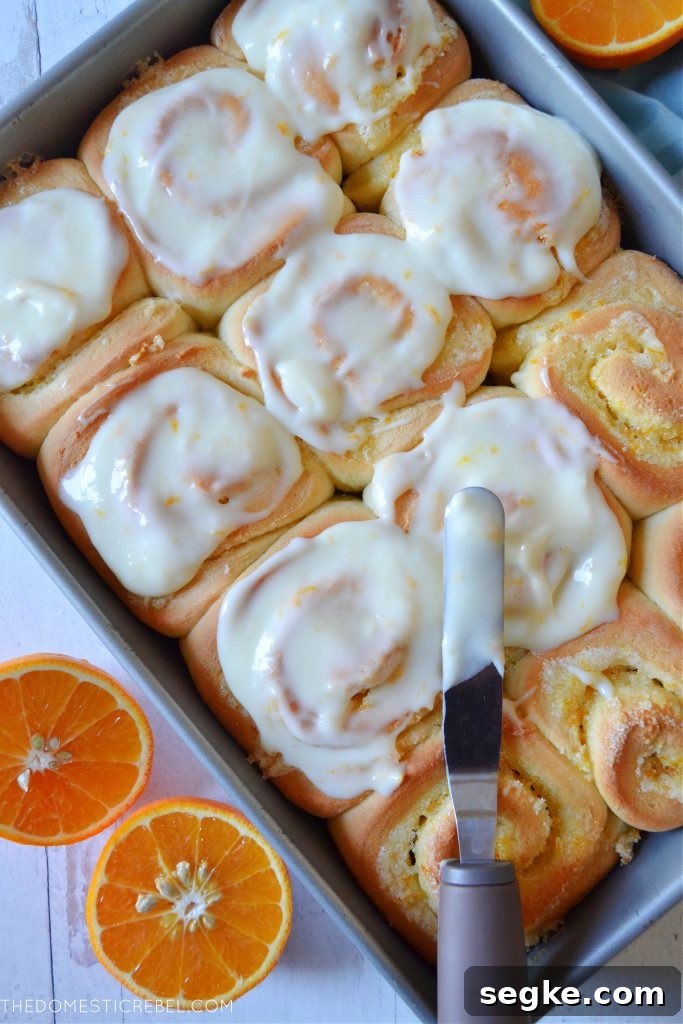 Zesty Orange Glazed Sweet Rolls Recipe 5 A pan filled with orange sweet rolls being frosted