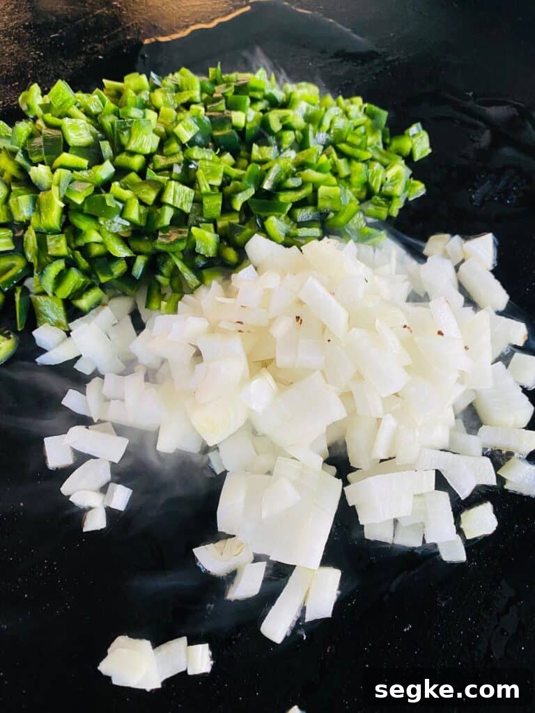onions and poblano peppers on the griddle before cooking