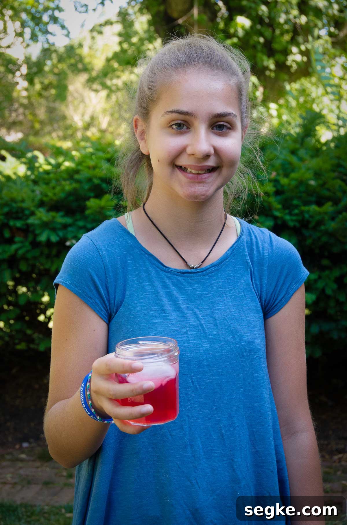 child standing outside smiling and holding a shirley temple