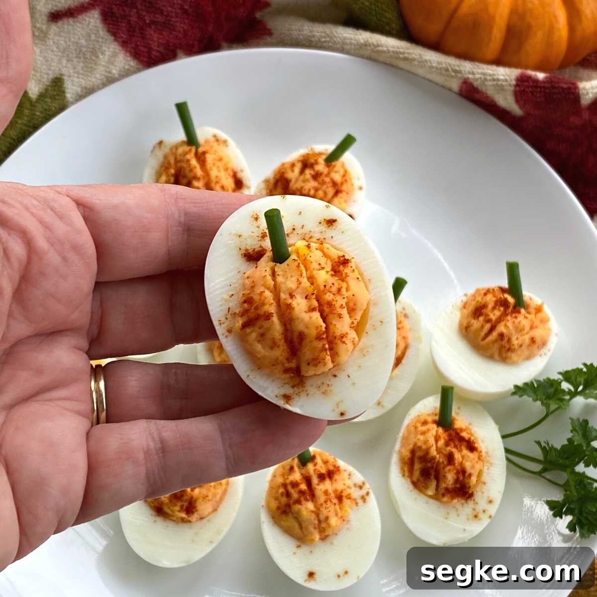 Hand holding a pumpkin deviled egg.