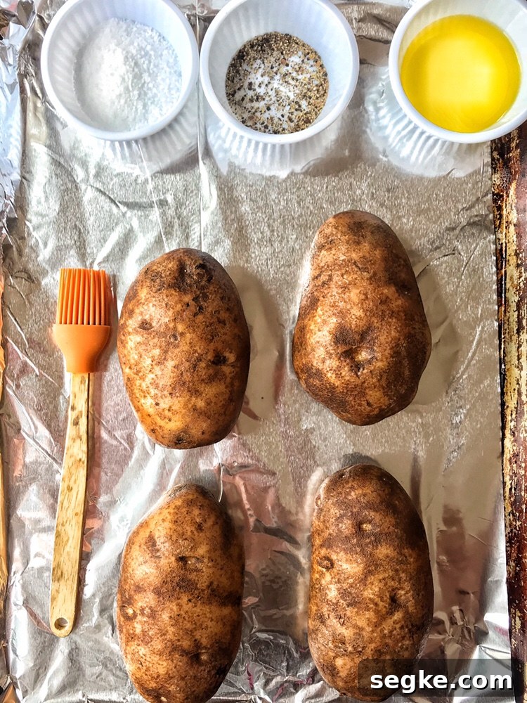 Potatoes, salt, pepper, melted butter, and a brush on a baking sheet
