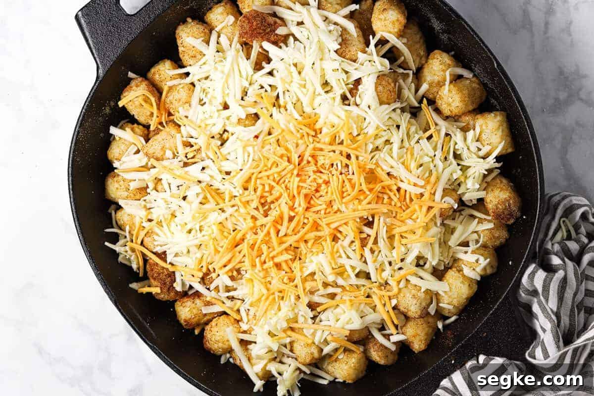 Tater tots in a cast iron skillet topped with shredded cheese