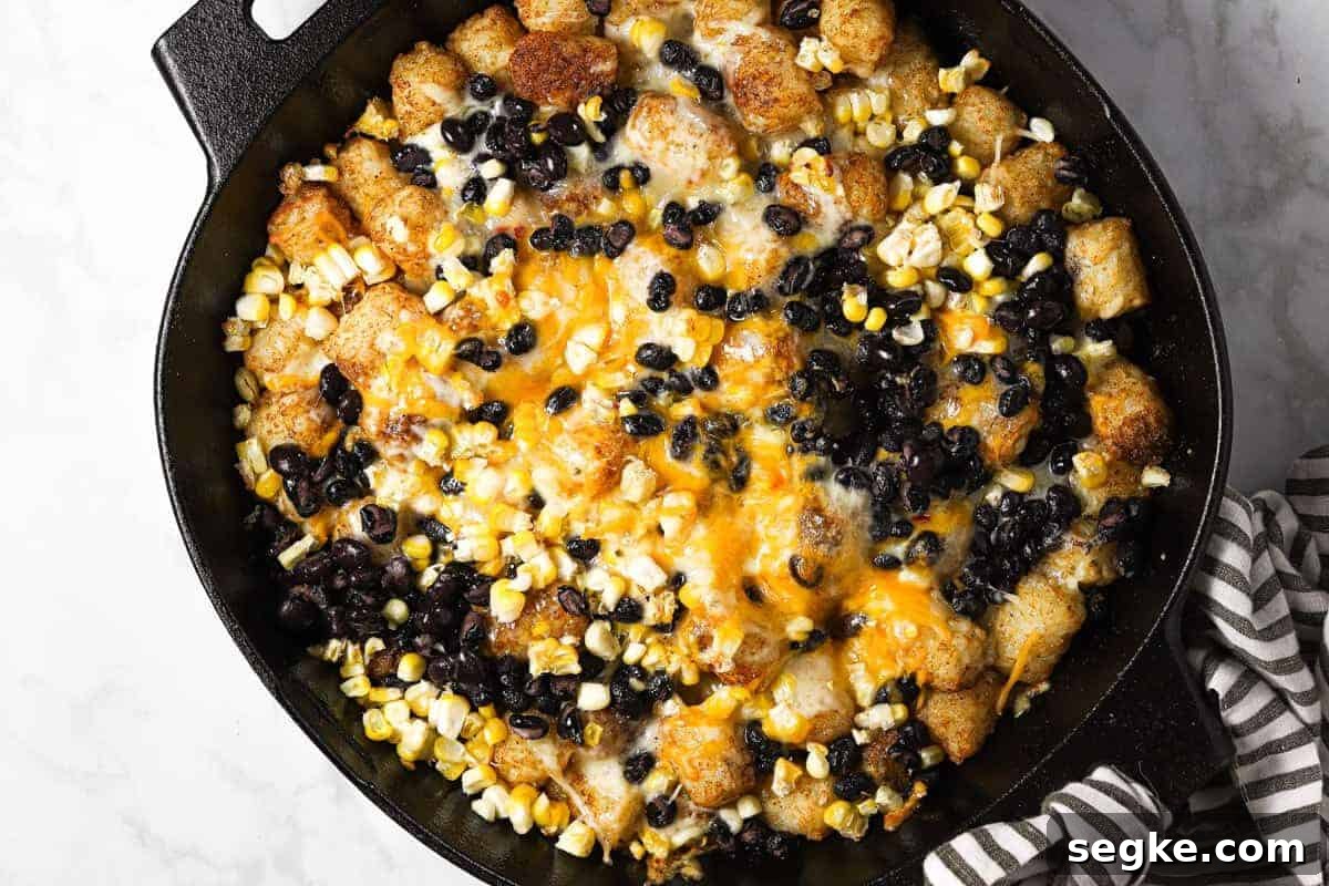 A cast iron skillet filled with freshly baked tater tot nachos 