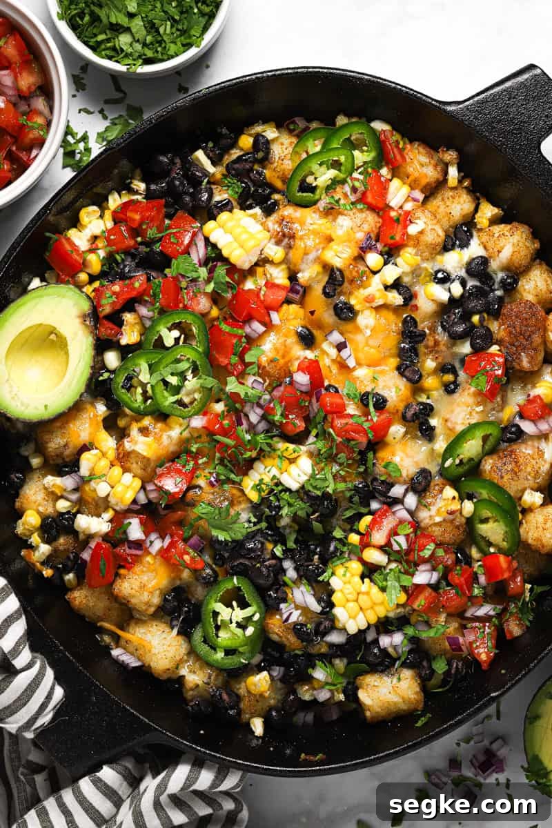 Large cast iron skillet with loaded vegetarian totchos garnished with cilantro