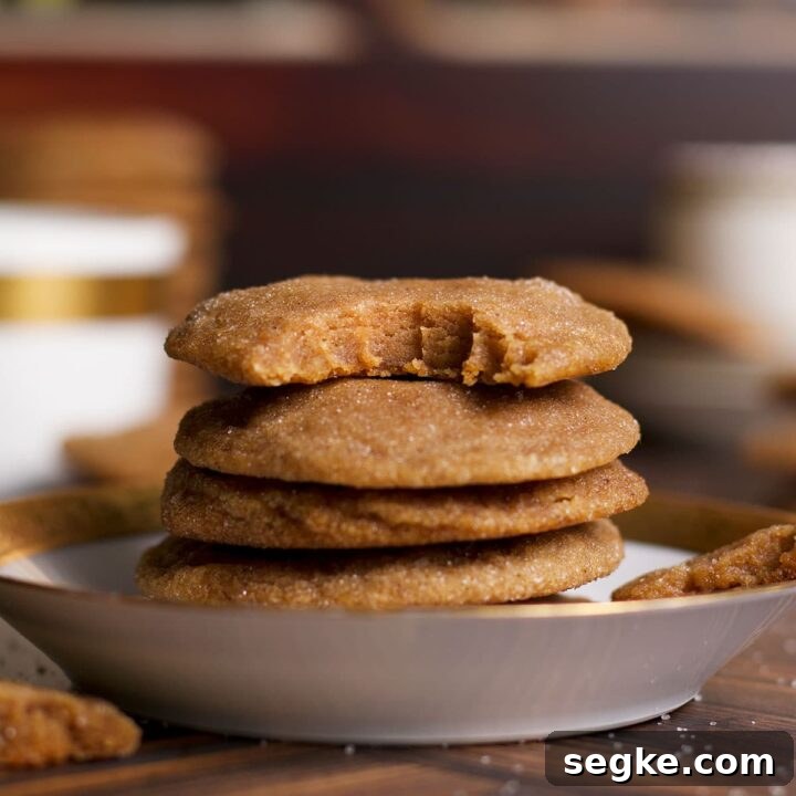 Several brown sugar cookies on a plate with a bite taken out of the cookie on the top of the pile.