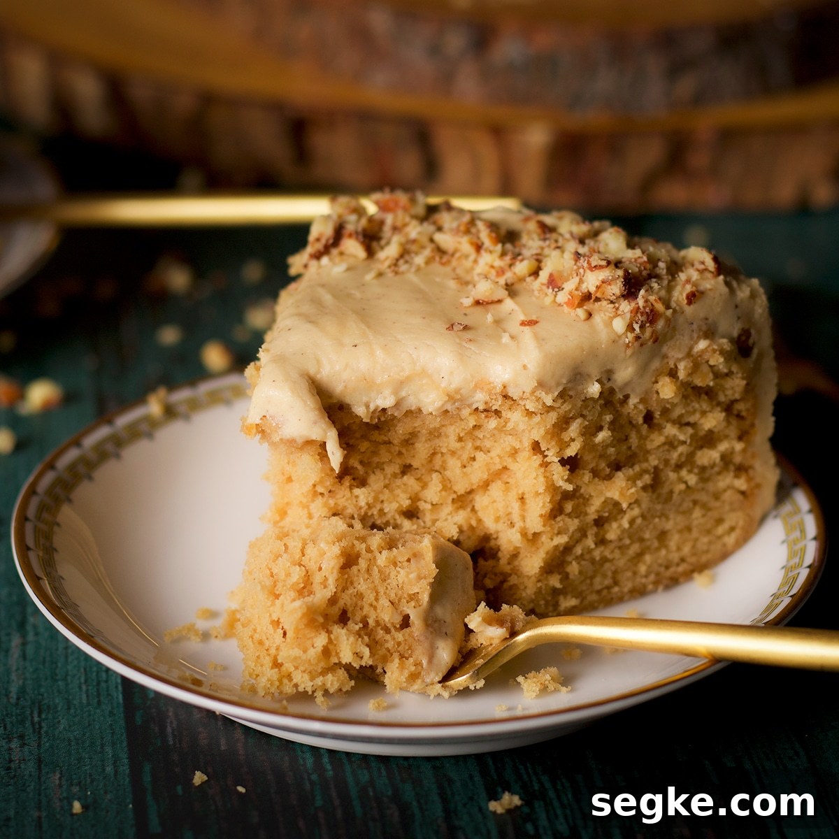 A slice of brown butter cake with maple miso brown butter frosting on a plate with a fork.