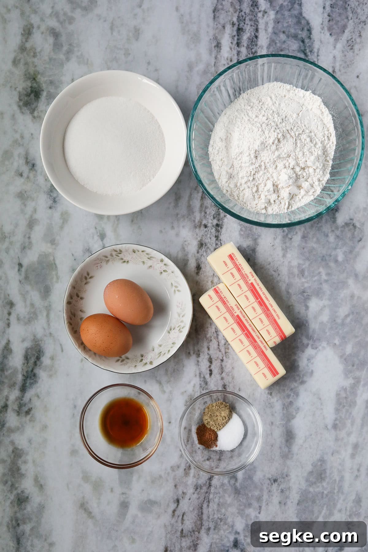 Ingredients for making cardamom butter cookies arranged on a marble table.