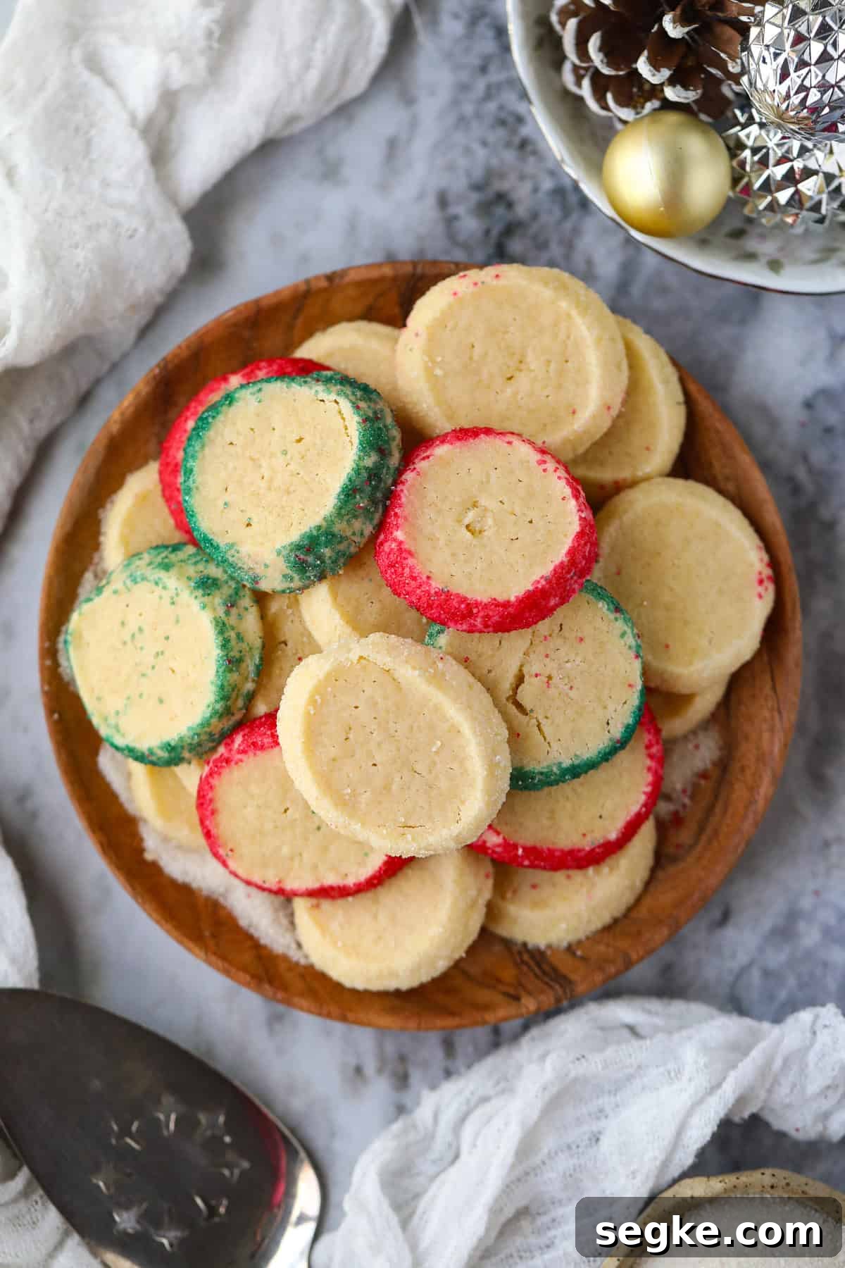 Cardamom butter cookies arranged on a wooden platter sitting on a table top.