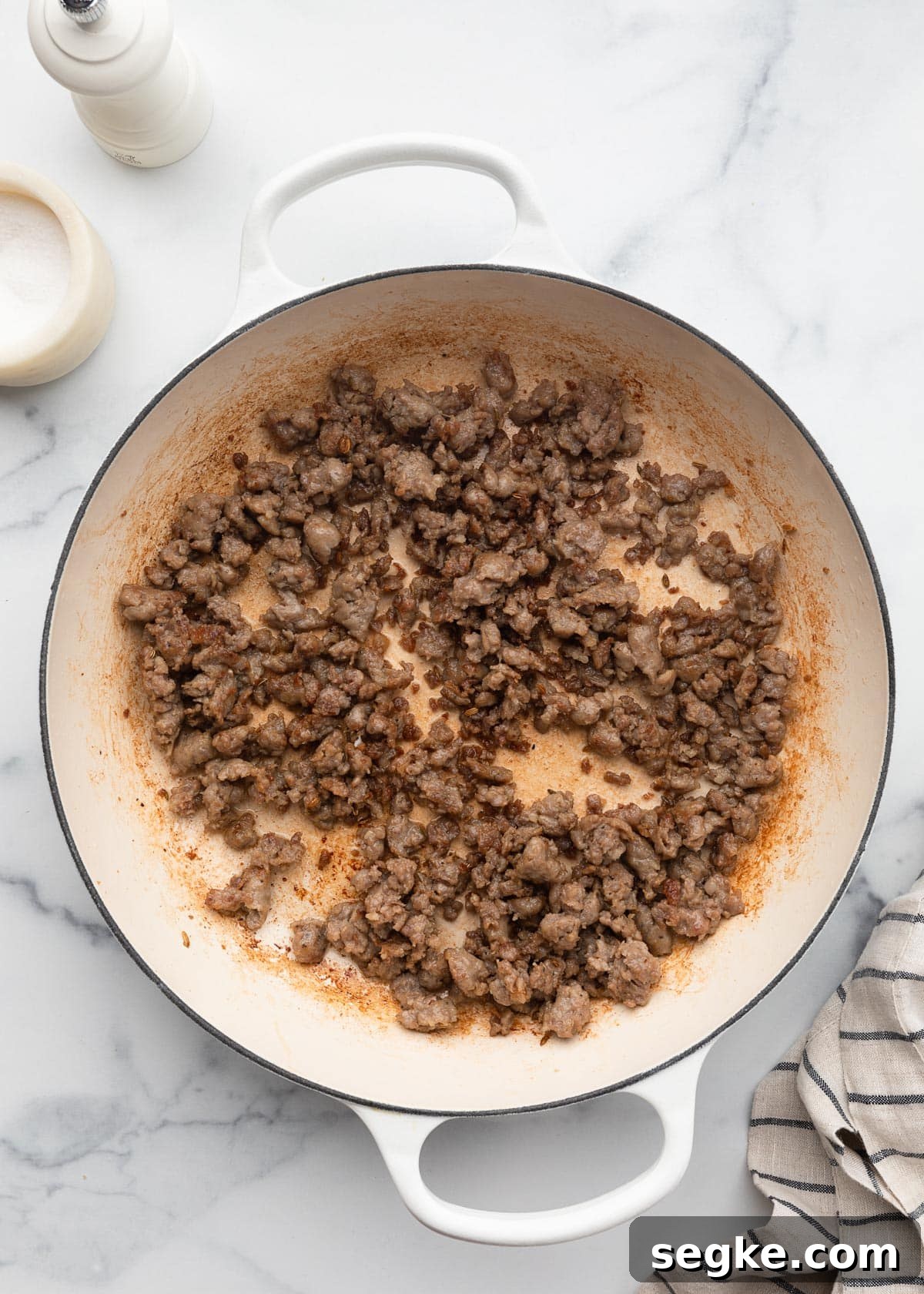 browned, crumbled Italian sausage in a white enameled cast iron pot