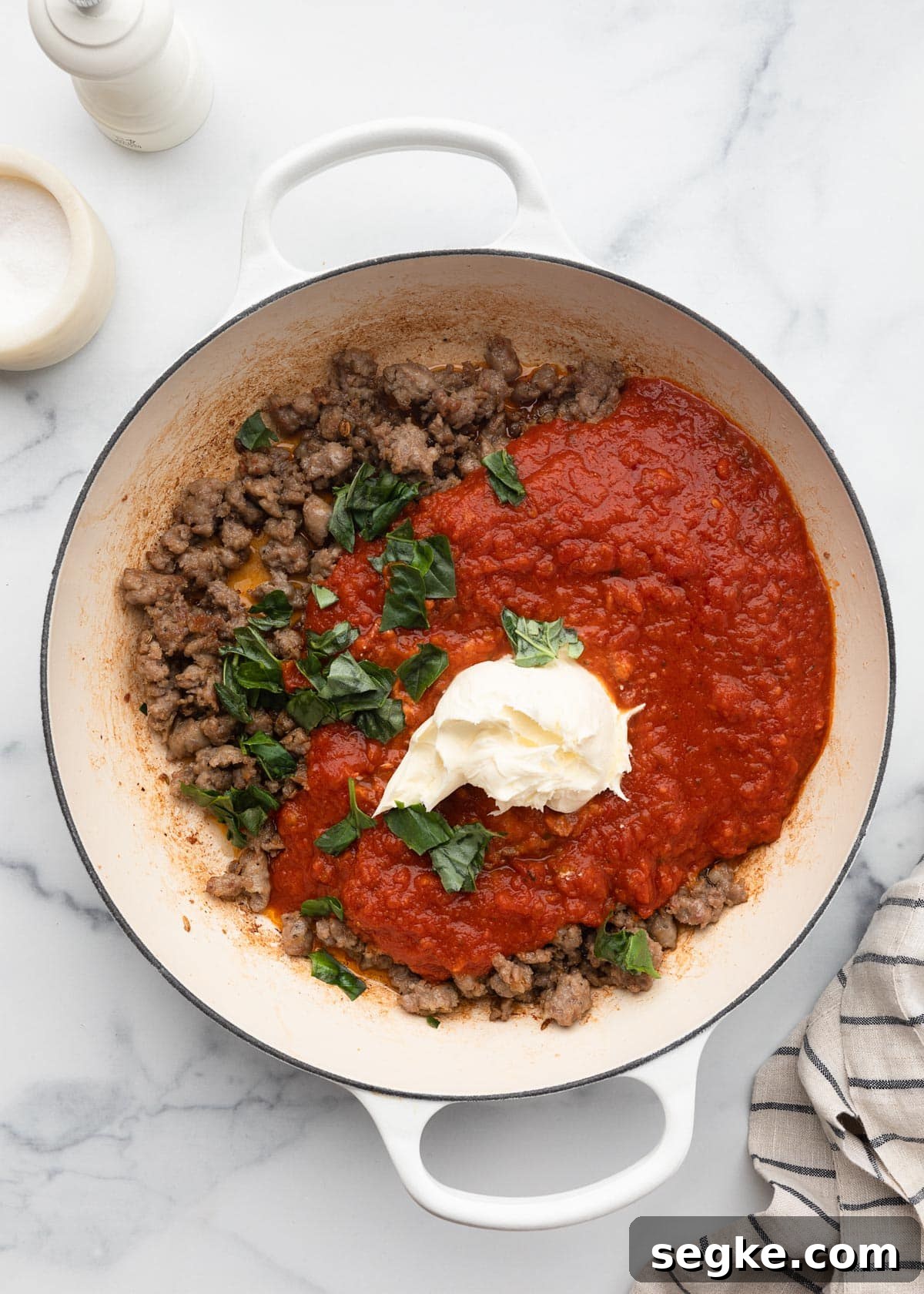 marinara sauce, browned crumbled sausage, mascarpone cheese, and torn basil leaves in a white enameled cast iron pot