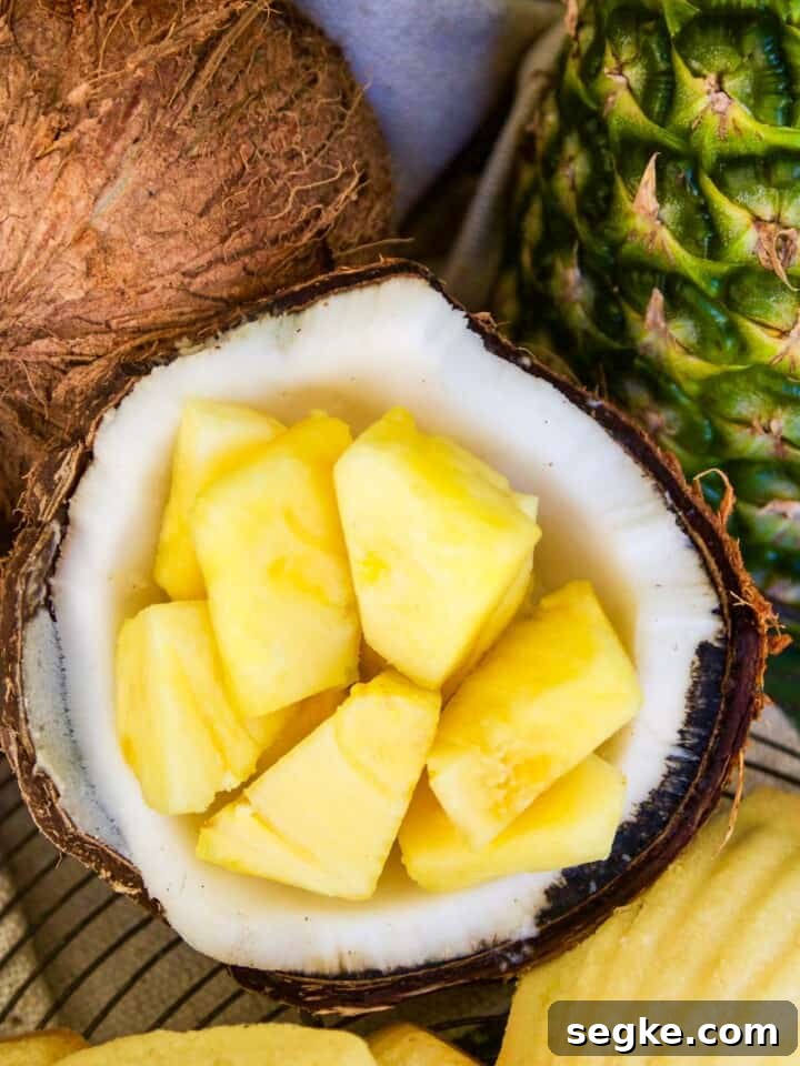 A coconut cracked open with fresh pineapple pieces inside