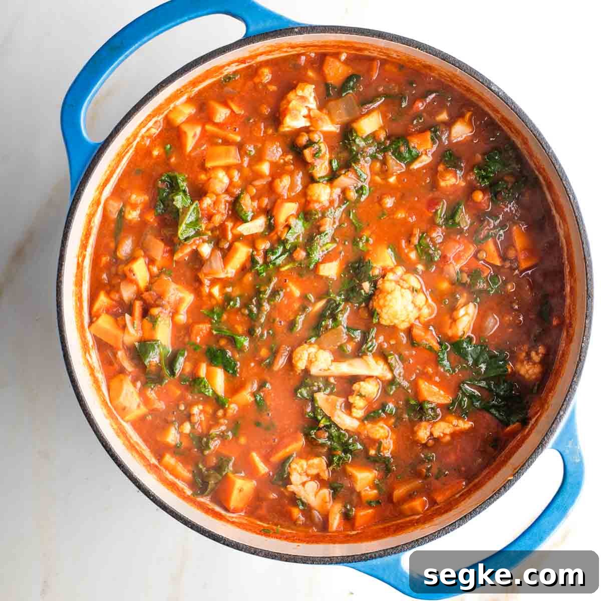 Wilted kale in a pot of chunky veggie stew.