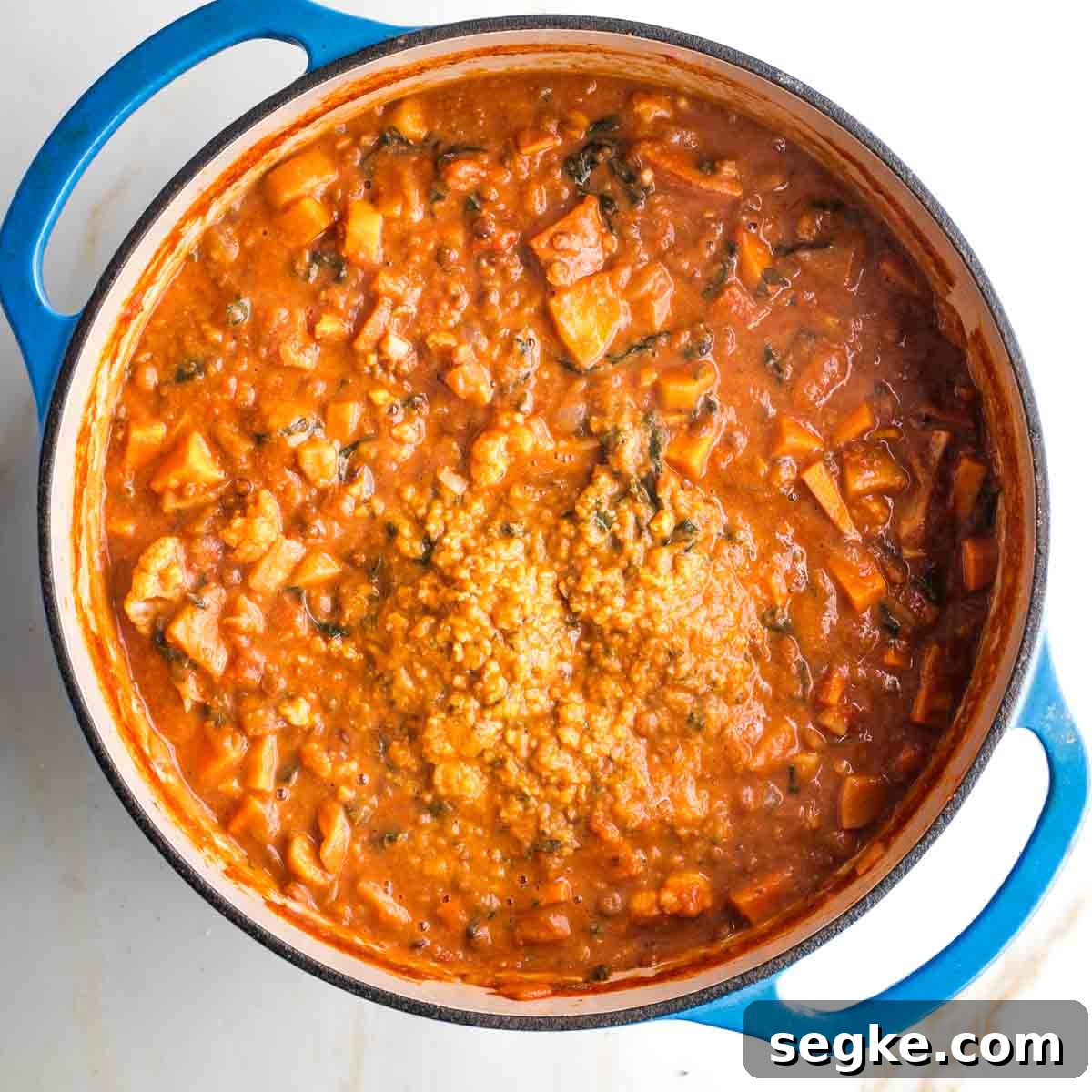 Dutch oven filled with chunky stew, and one section that has been pureed into a creamy base.