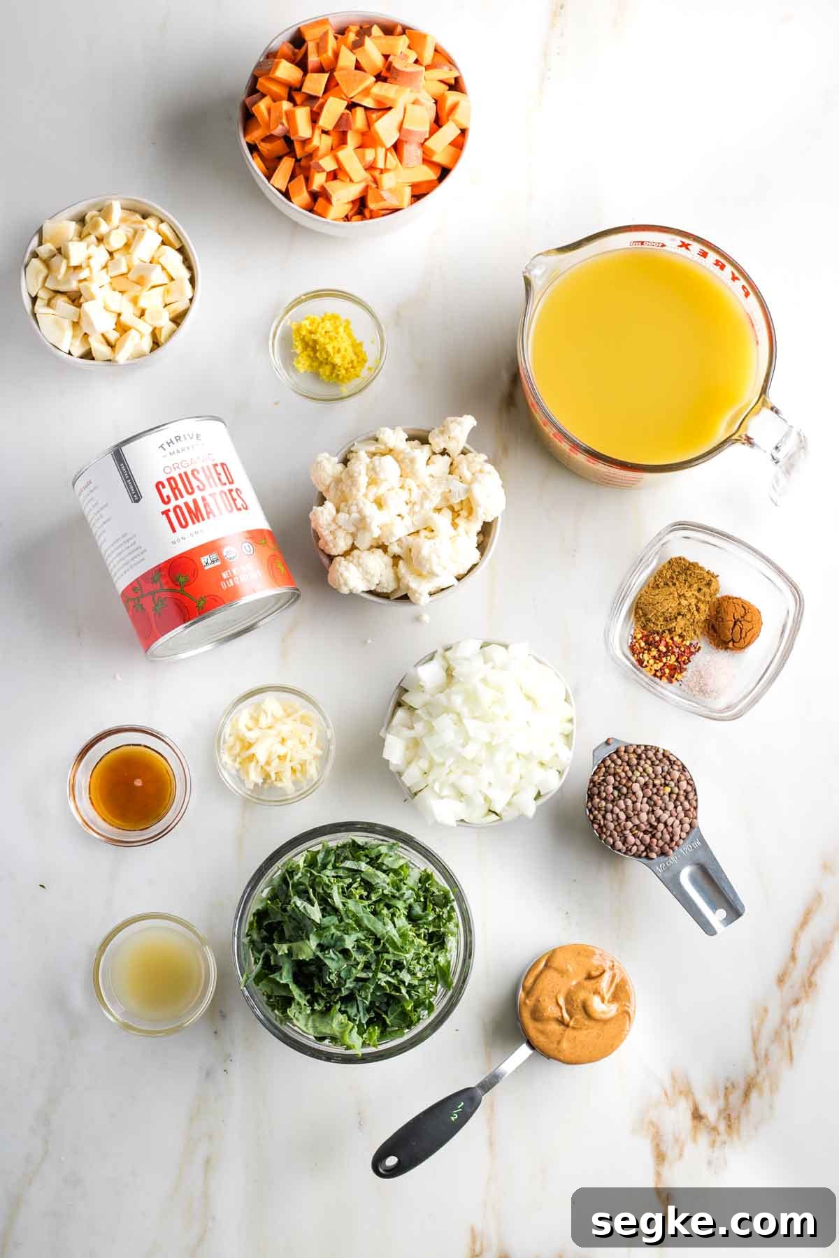 Chopped veggies in bowls, plus other ingredients laid out to make vegan peanut butter stew.