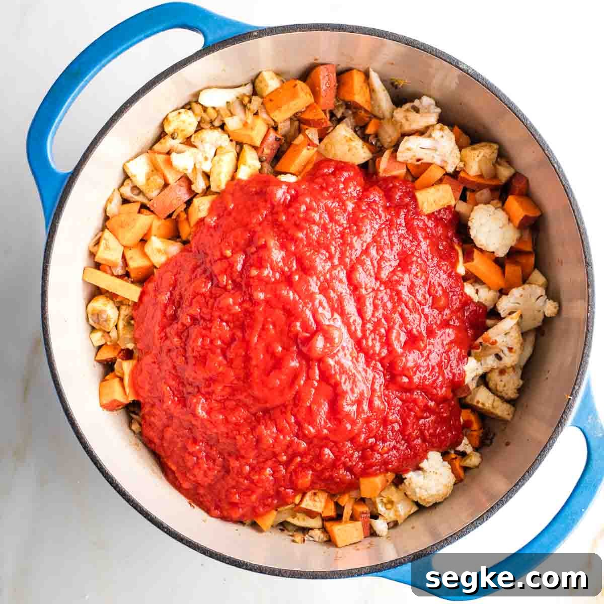 Crushed tomatoes on top of sauteed veggies in a dutch oven.