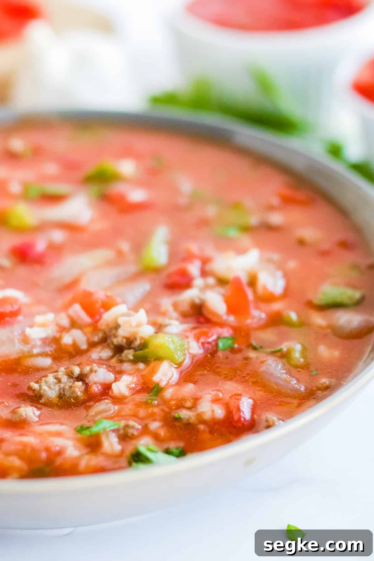 A close-up bowl of stuffed pepper soup loaded with ground beef, rice, green peppers, and a rich tomato broth.