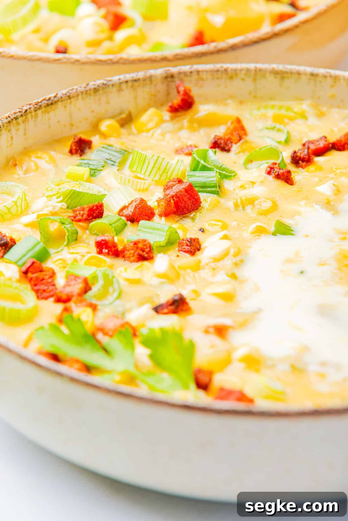 A pot of creamy corn chowder topped with crispy bacon and green onion.