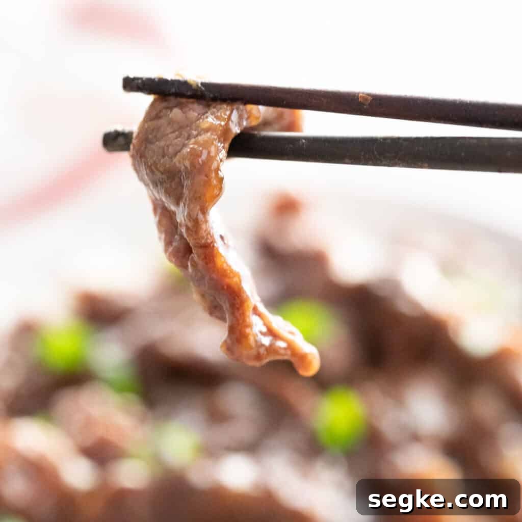 chopsticks holding piece of Mongolian beef