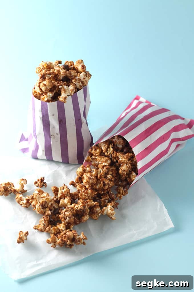 Salted Caramel Chocolate Popcorn Recipe 3 two striped bags filled with salted caramel chocolate popcorn on a blue background