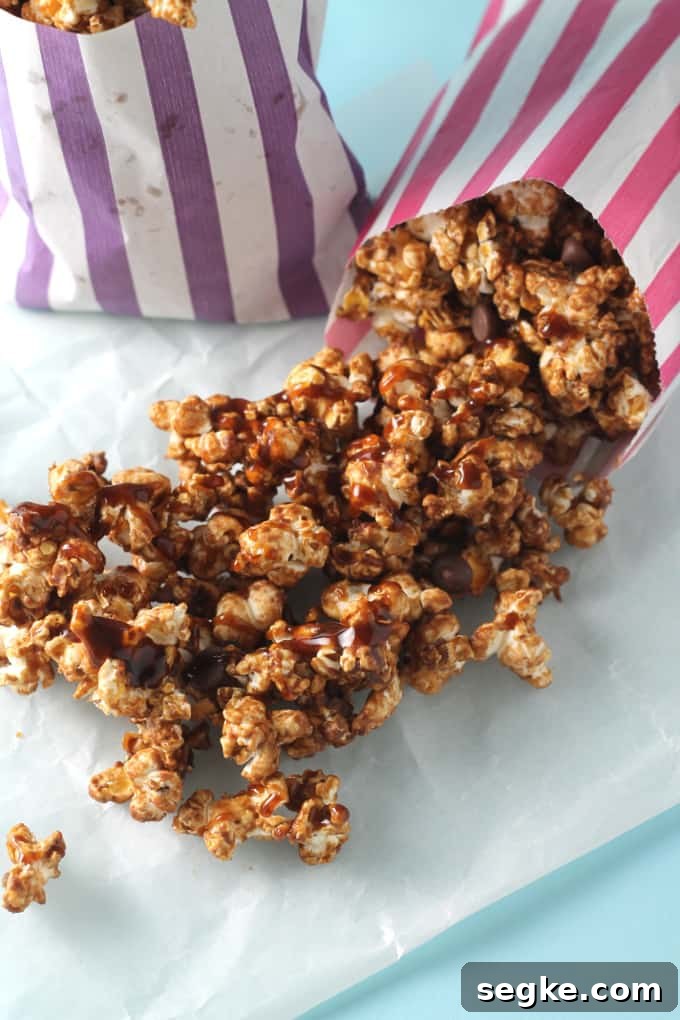 Salted Caramel Chocolate Popcorn Recipe 4 salted caramel chocolate popcorn falling out of a pink striped paper bag