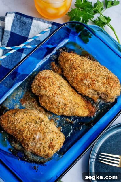 Golden brown, oven-fried chicken breast on a blue glass baking dish.