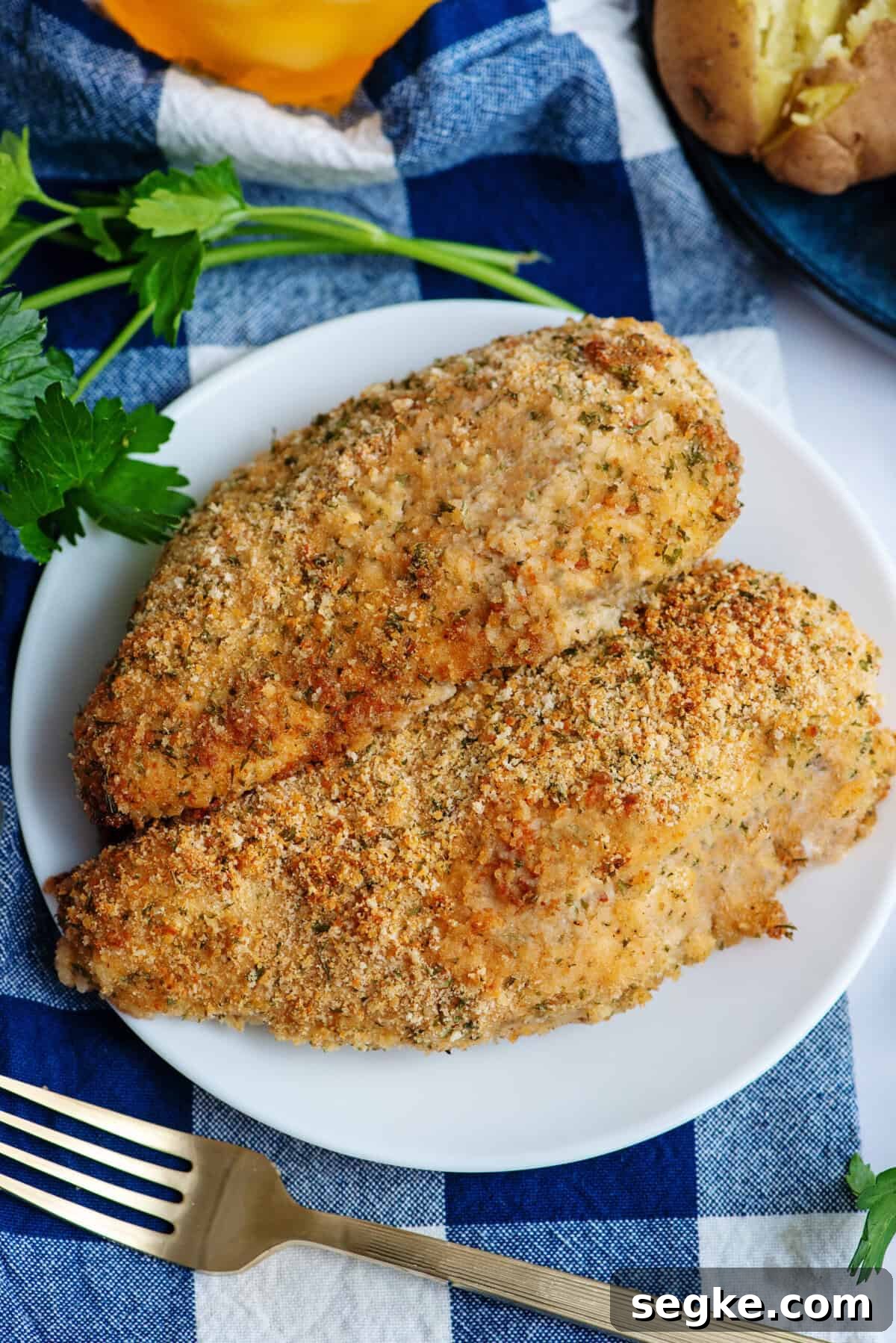 Two golden brown oven-fried chicken breasts on a white plate.