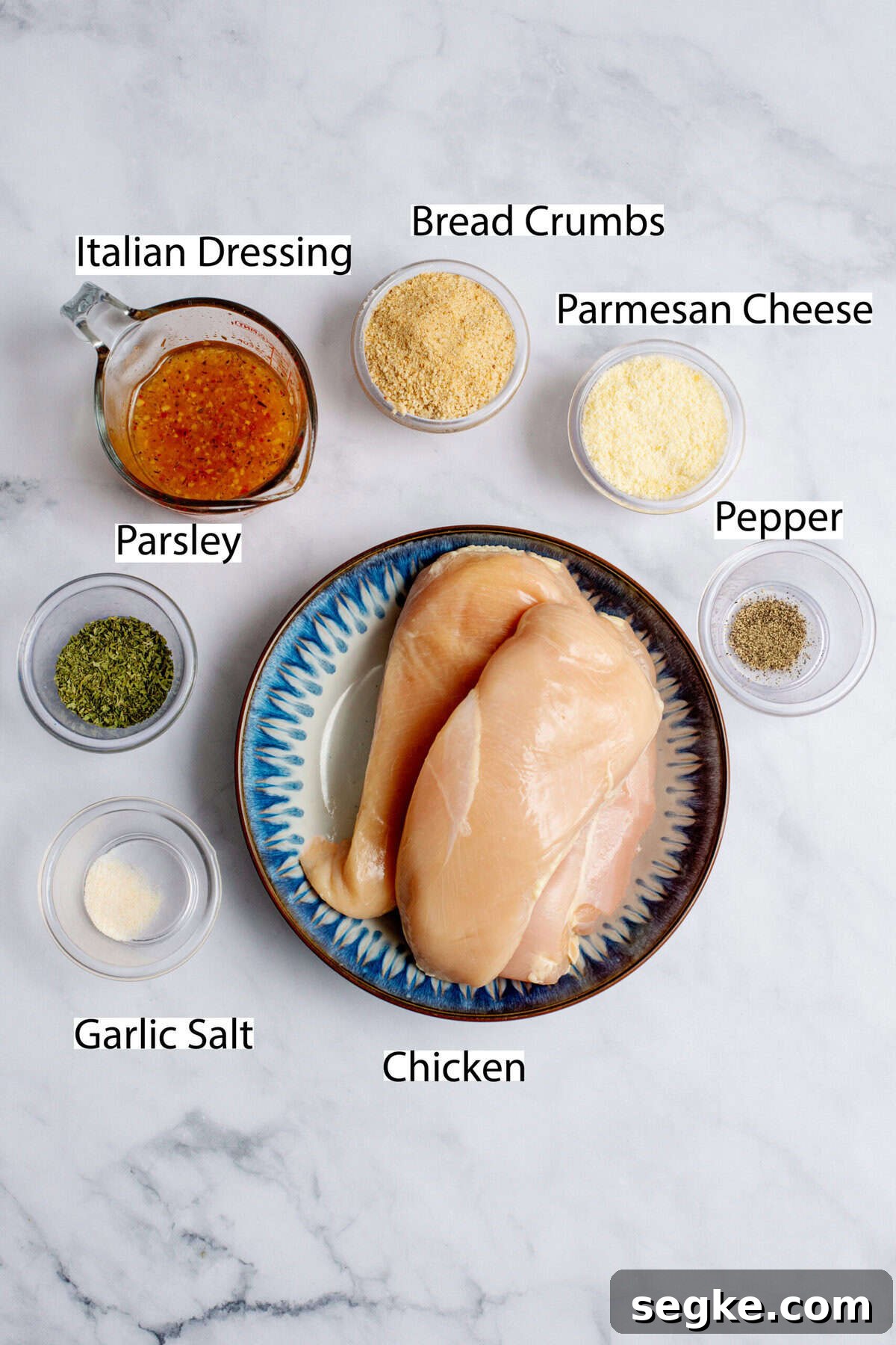 Ingredients for oven-fried chicken on a white marble surface.