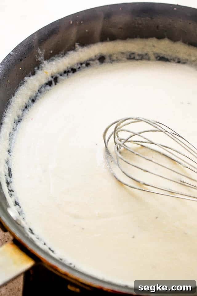 whisking cream cheese sauce in a black skillet