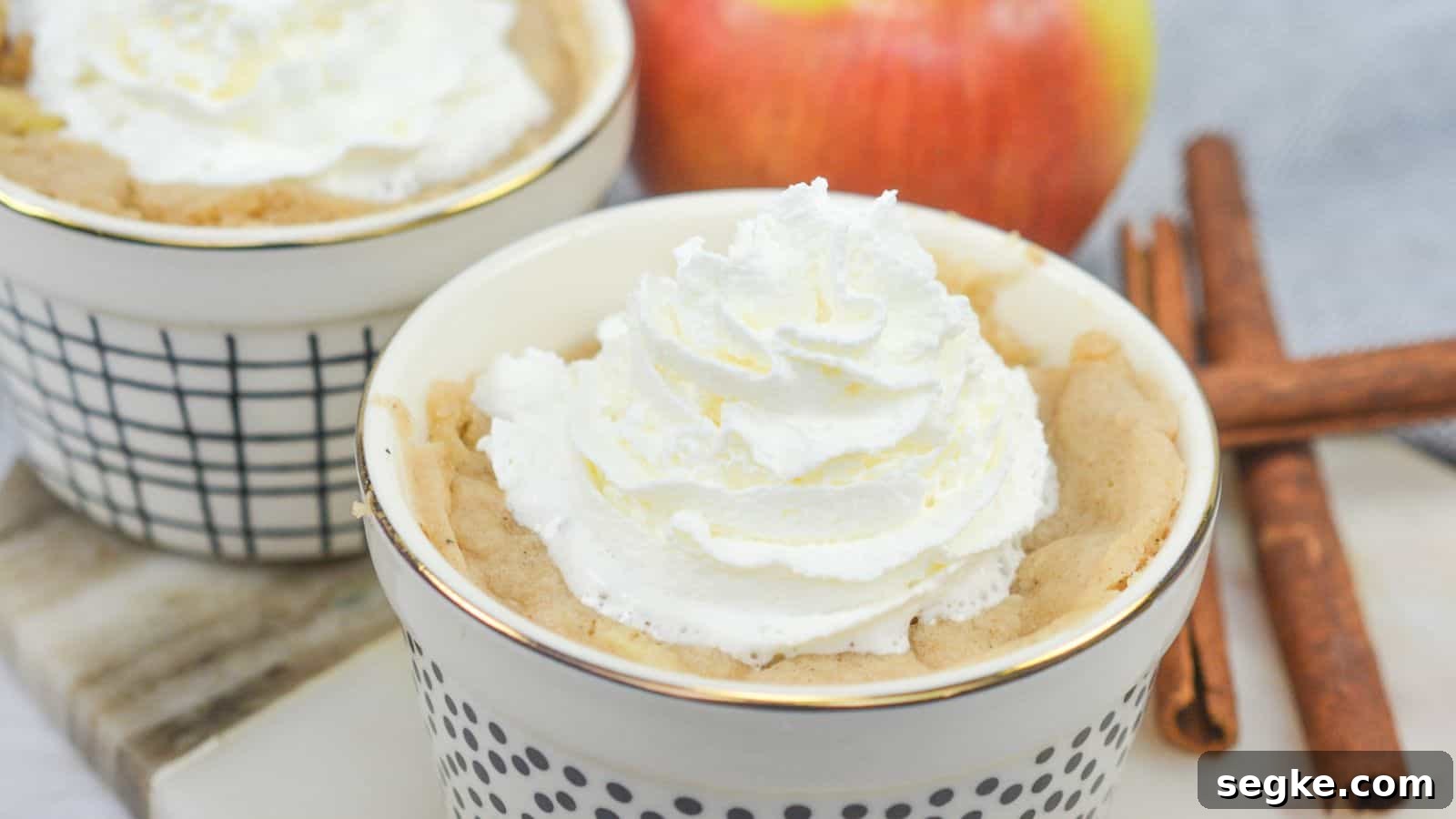 Apple mug cakes in ramekins with cinnamon sticks.