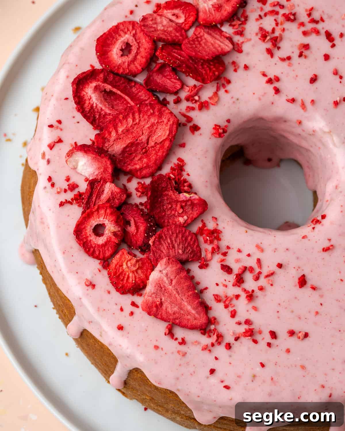 A strawberry pound cake topped with pink icing and freeze dried strawberries. 