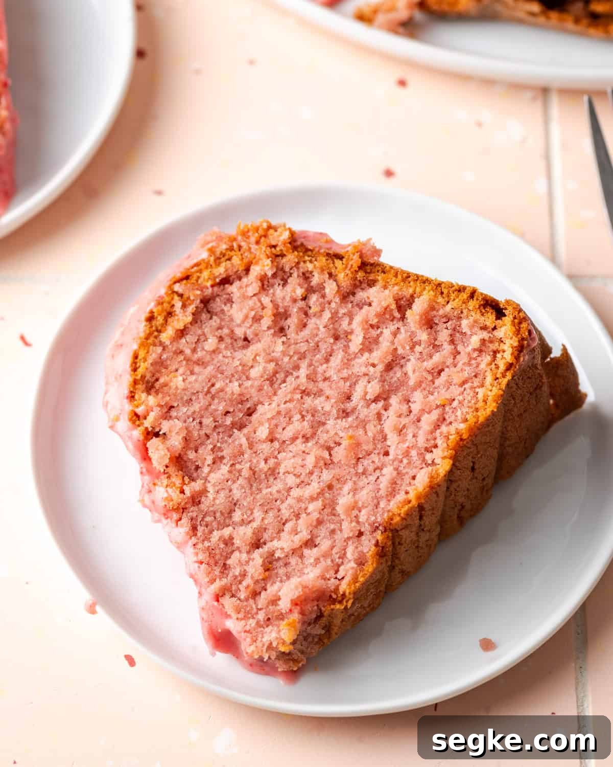 A single slice of strawberry pound cake on a white plate.