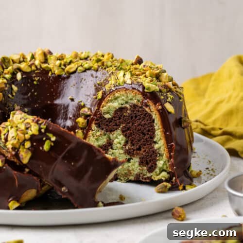 A sliced chocolate pistachio cake showing the green and brown swirls inside.
