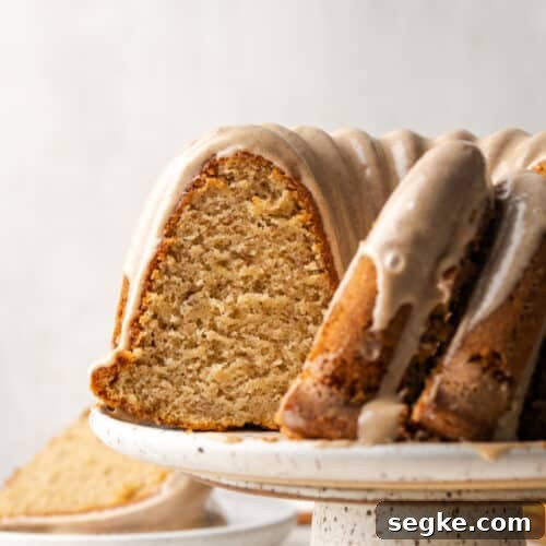 A gluten free banana cake sliced and sitting on a white cake stand.