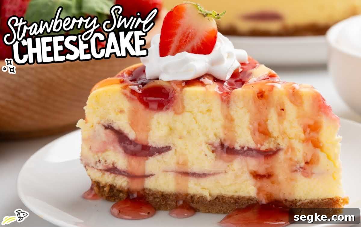 Strawberry swirl cheesecake slice topped with whipped cream and a fresh strawberry, showing thick cheesecake layers and swirl