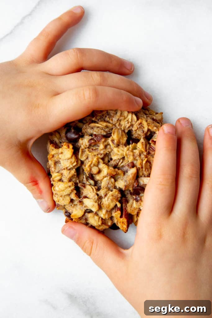 Banana Oat Breakfast Cookies - Gluten-Free Vegan 9 A child's hand holding a banana breakfast cookie.