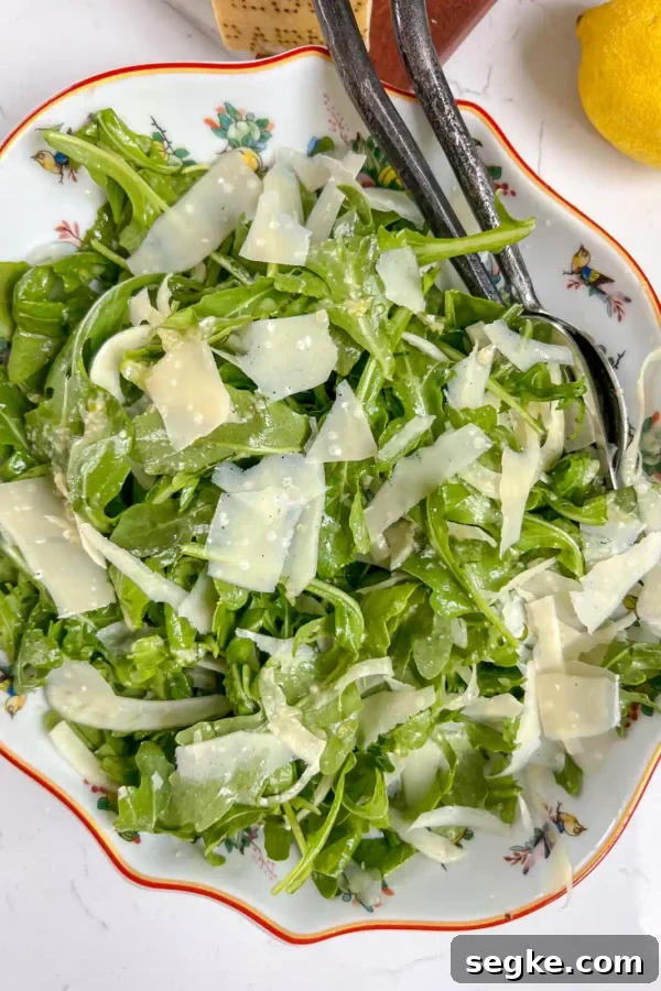 A bowl of arugula fennel salad tossed with honey dijon dressing and shaved parmesan.
