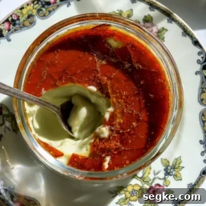 A spoon breaking through the hard caramel shell of a creamy pistachio creme brulee made without a kitchen torch.