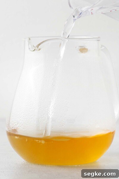 Refreshing Chamomile Iced Tea with Honey and Lemon 6 Pouring water into tea in a teapot.