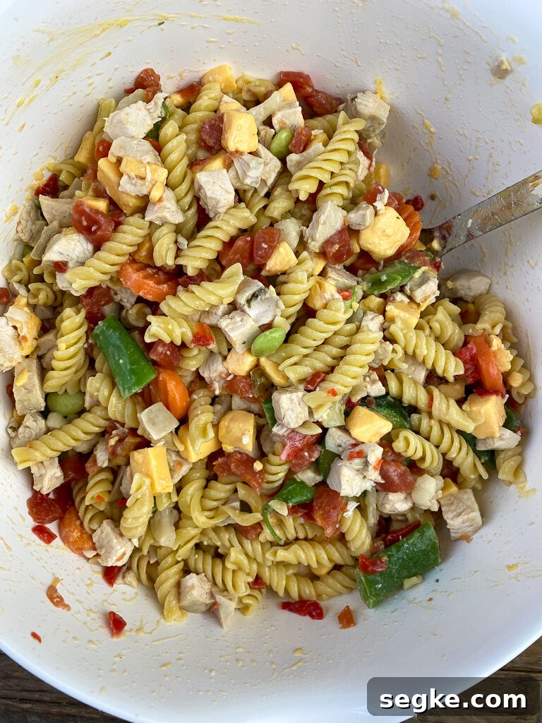 Large spoon mixing together chicken, velveeta cheese, vegetables and rotel to make a Velveeta chicken casserole.