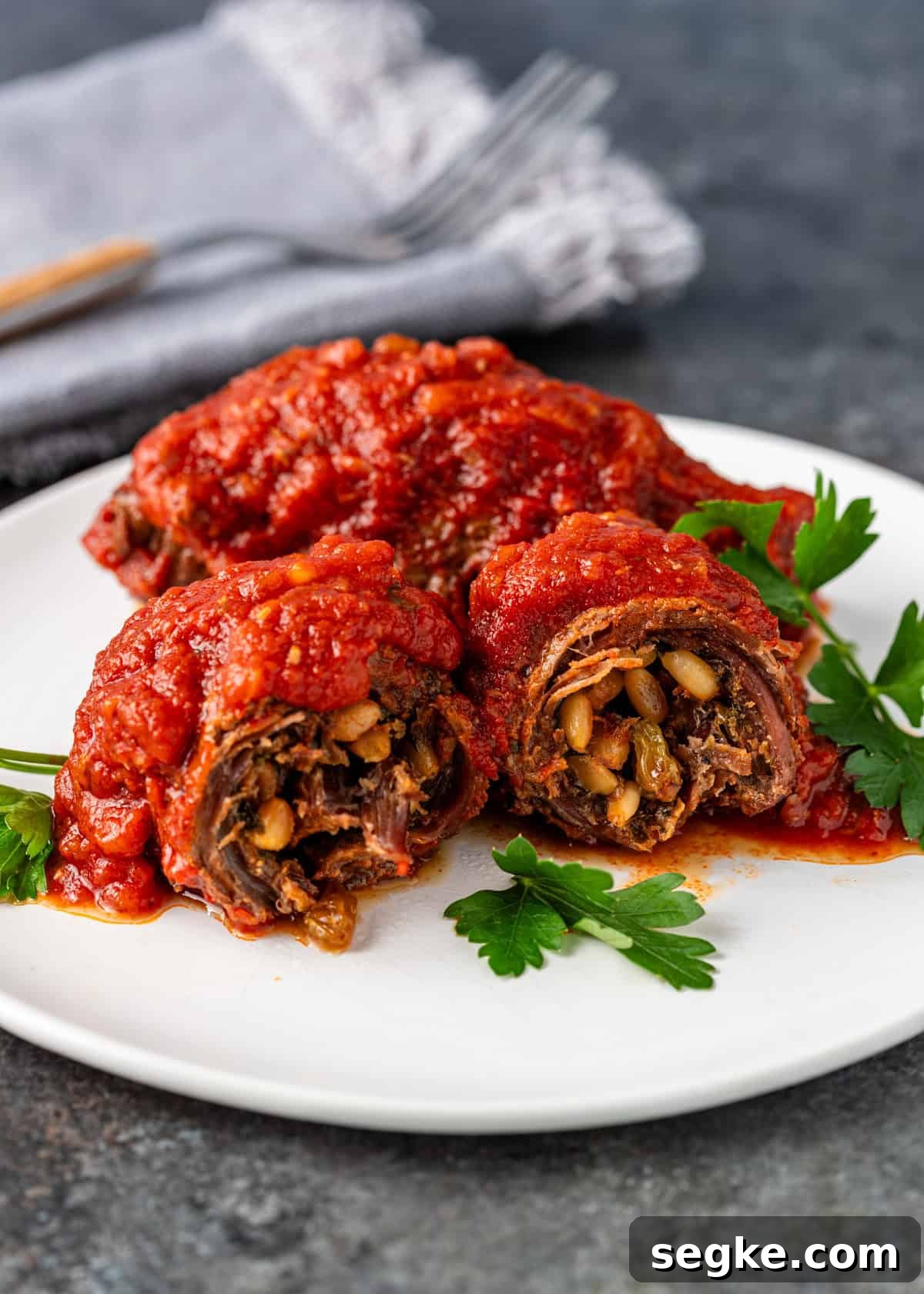 closeup side view: braciole on white plate