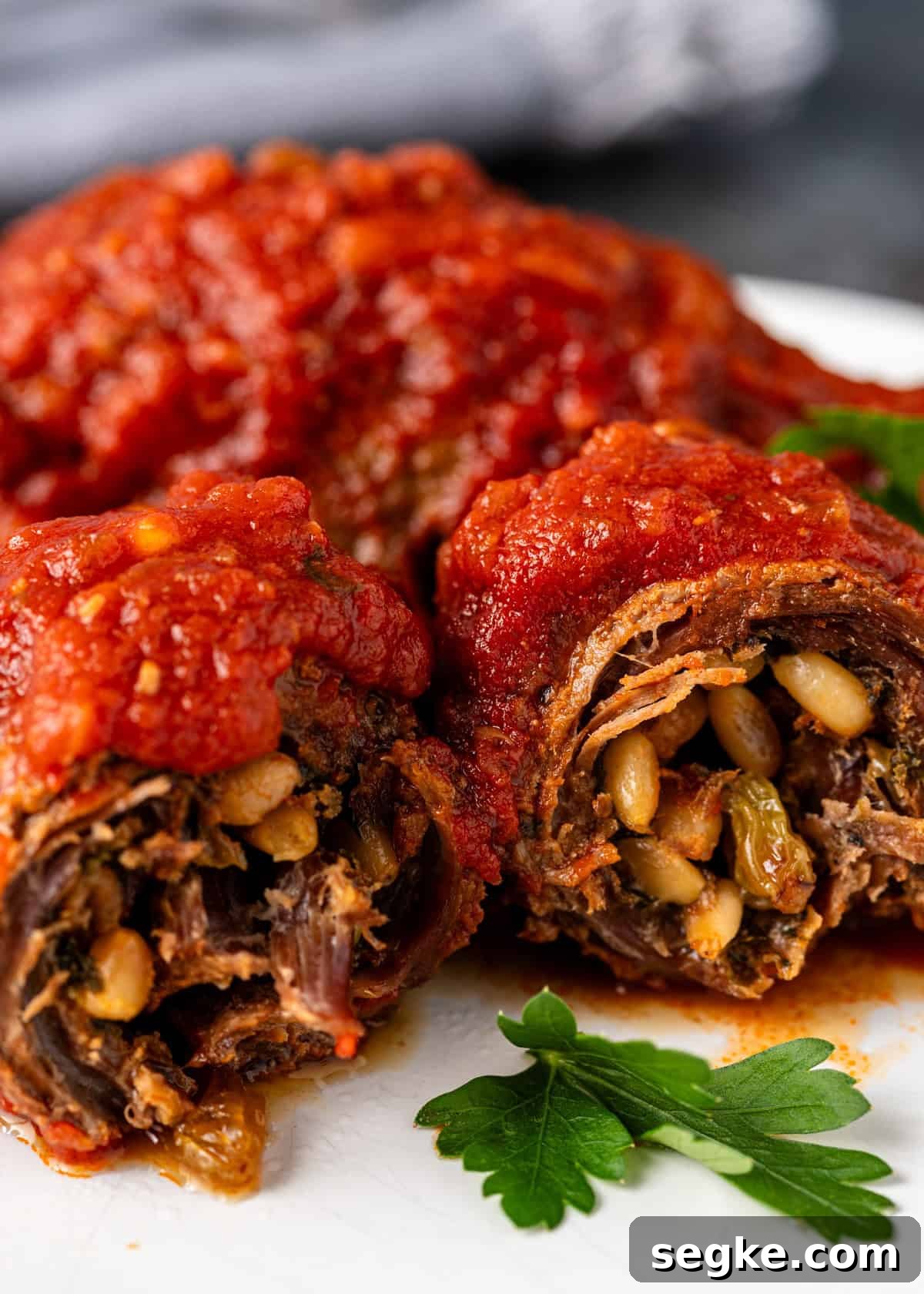 closeup side view: ready to eat beef braciole on white plate