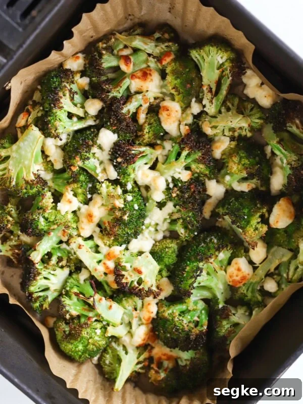 Air fryer broccoli and feta cheese in an air fryer basket.